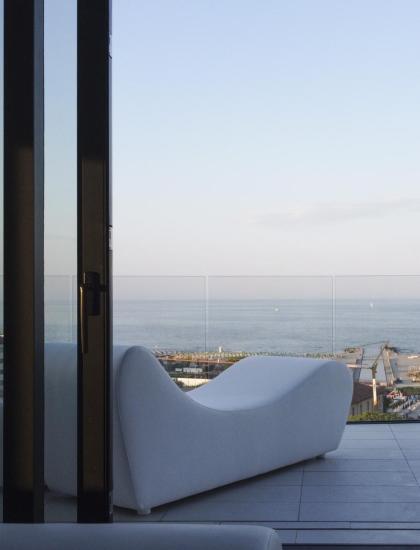 Vista sul mare da un balcone con divano bianco.