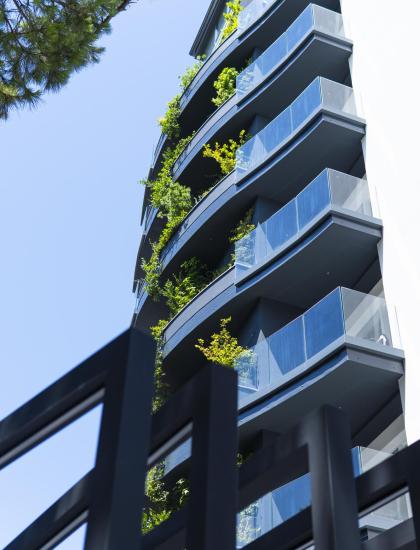 Edificio moderno con balconi verdi e cielo blu limpido.
