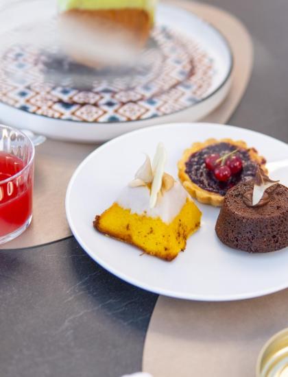 Dolci deliziosi su un piatto: tortino, crostata e dolce al cocco, con succhi colorati.