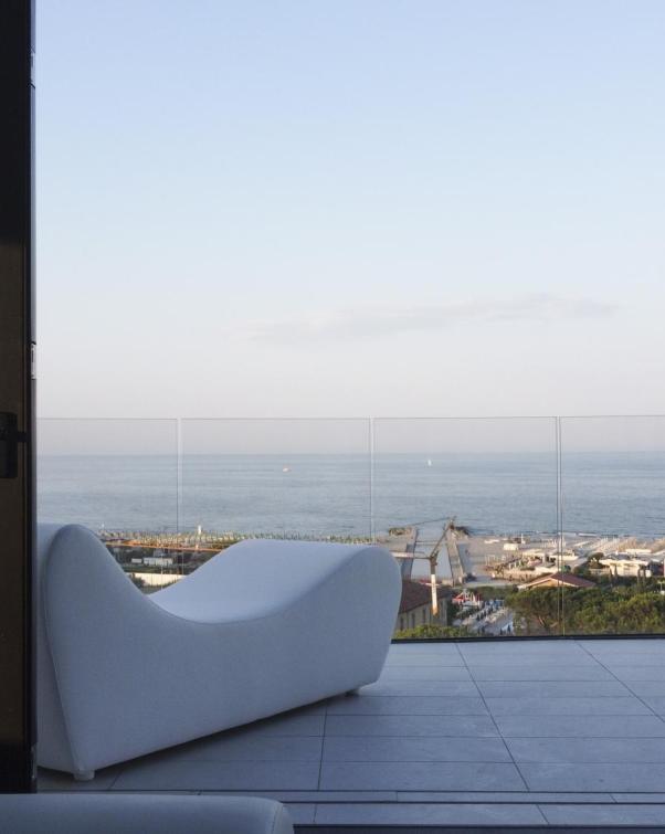 Vista sul mare da un balcone con divano bianco.