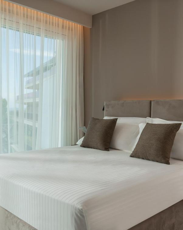 Camera moderna con letto matrimoniale e ampie finestre.