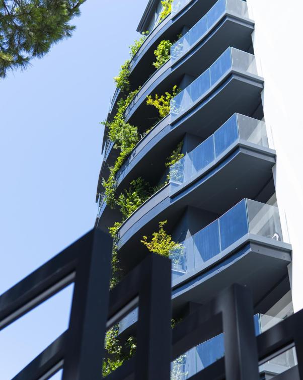 Edificio moderno con balconi verdi e cielo blu limpido.