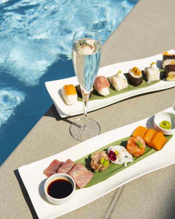 Sushi elegante e champagne a bordo piscina, atmosfera di lusso e relax.