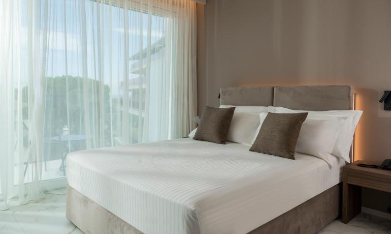 Camera moderna con letto matrimoniale e ampie finestre.
