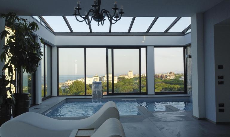 Piscina interna con vista panoramica sul mare e la città.