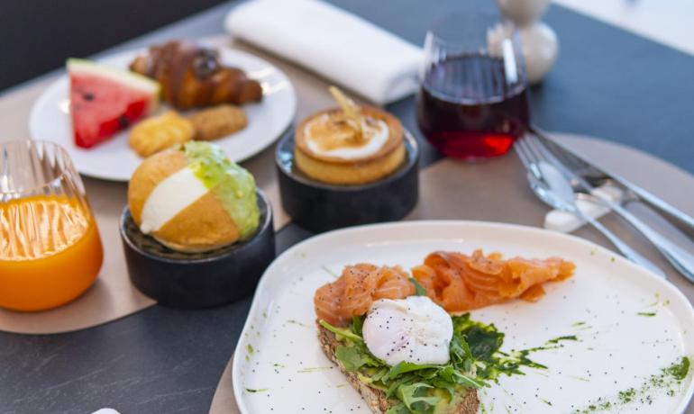 Colazione raffinata con salmone, uova, dolci e bevande colorate.