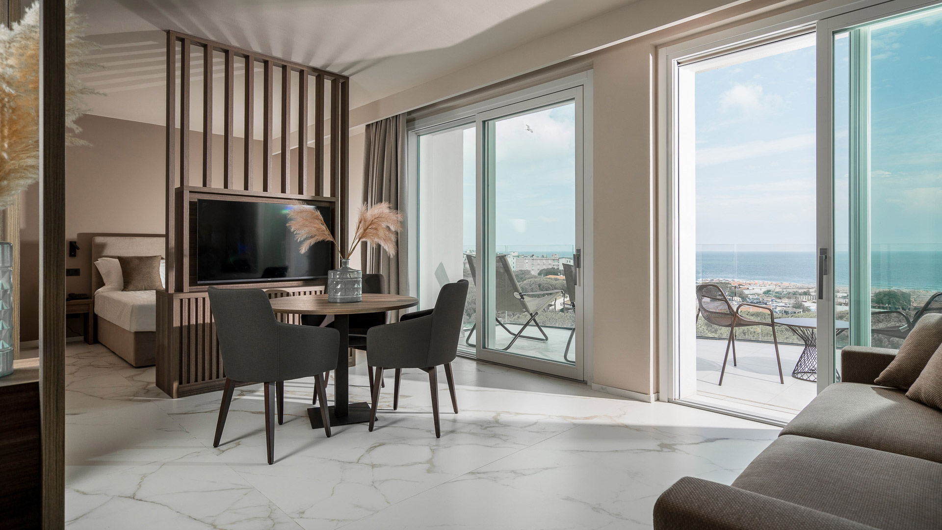 Elegante suite moderna con vista mare, luce naturale e arredi raffinati.