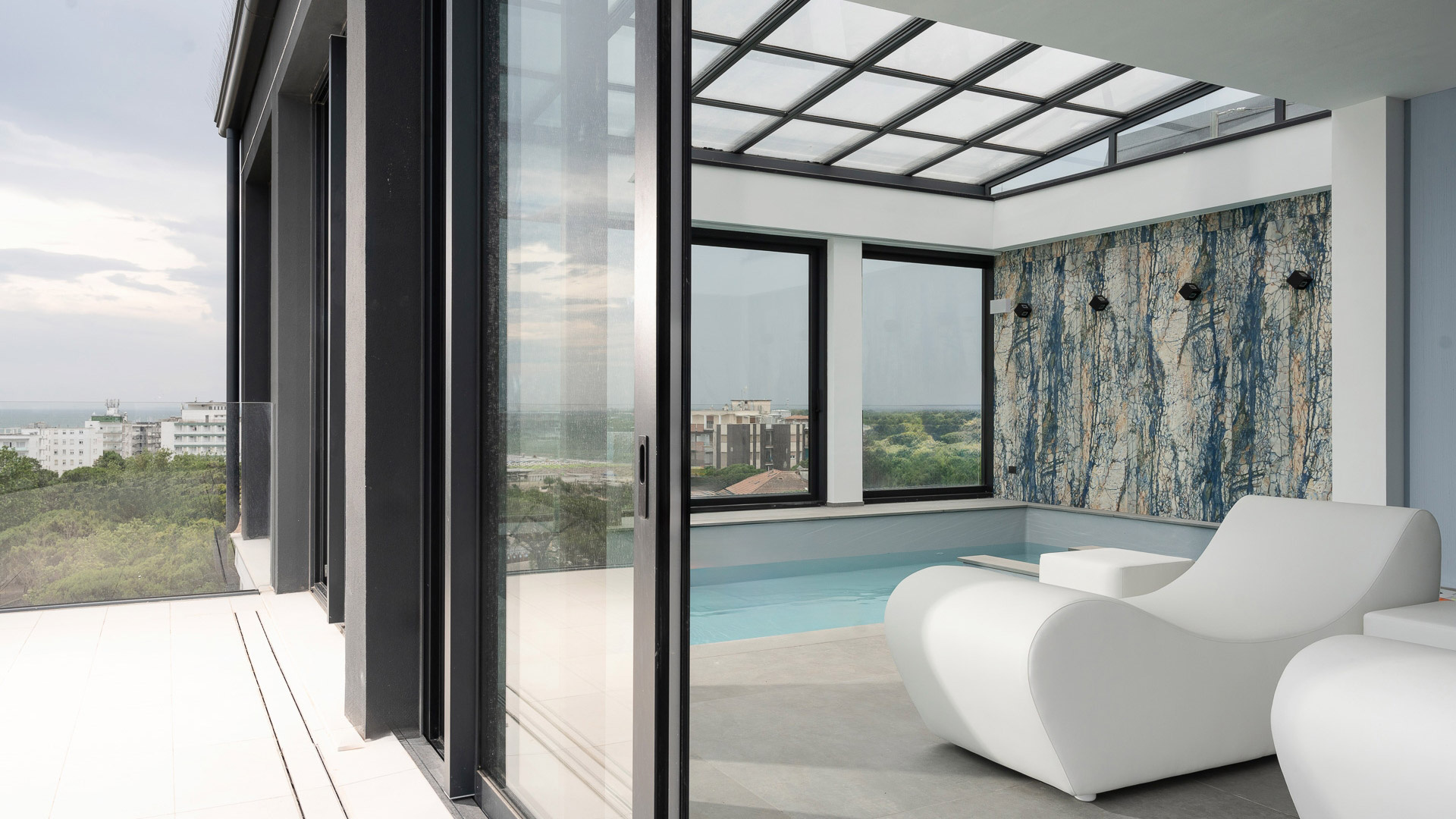 Elegante terrazza con piscina, vista panoramica, poltrona moderna e parete artistica.