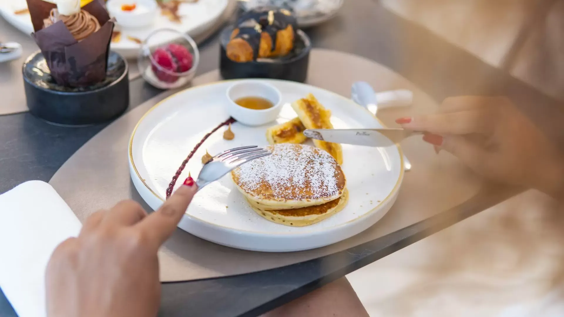 Colazione con pancake, sciroppo e dolci su un tavolo elegante.