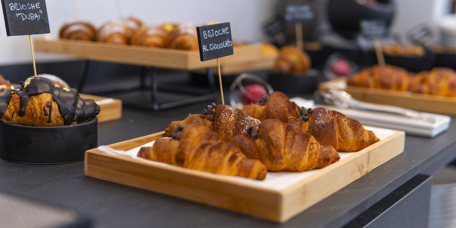 Vassoio di brioche dorate, alcune ricoperte di cioccolato, su un elegante buffet.