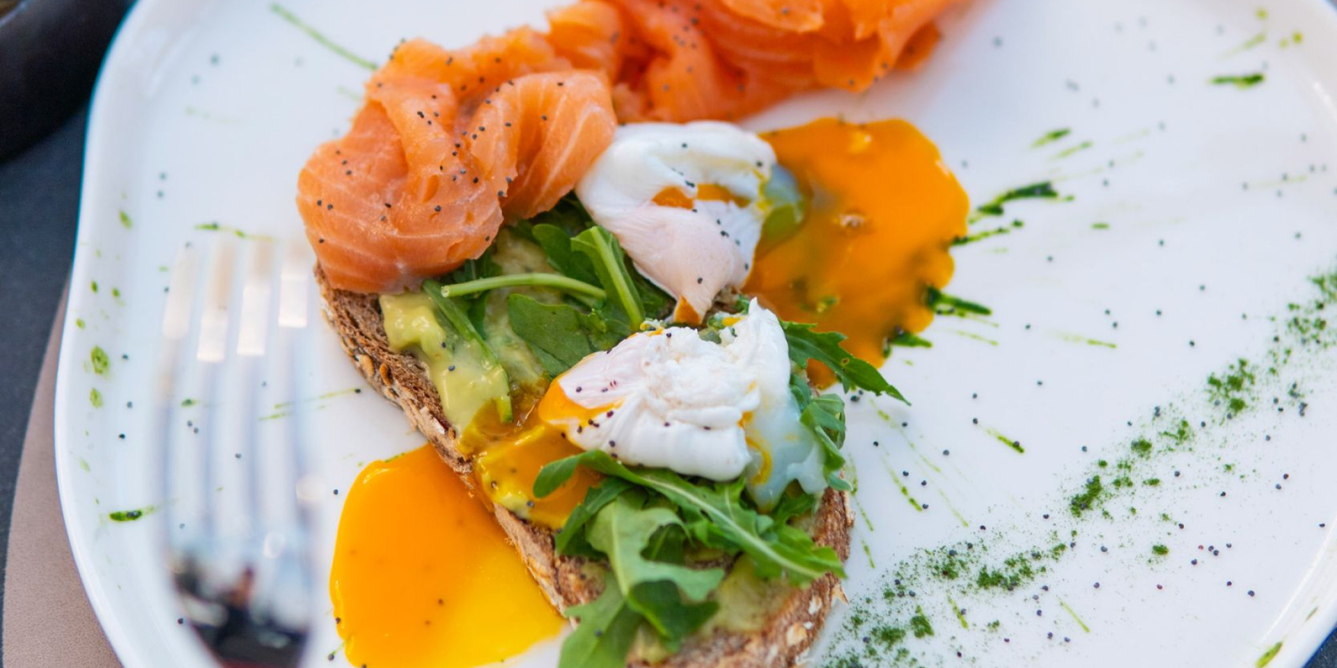 Bruschetta gourmet con salmone, uova in camicia e avocado, elegante e invitante.