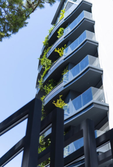 Edificio moderno con balconi curvi e piante rampicanti, atmosfera fresca e naturale.