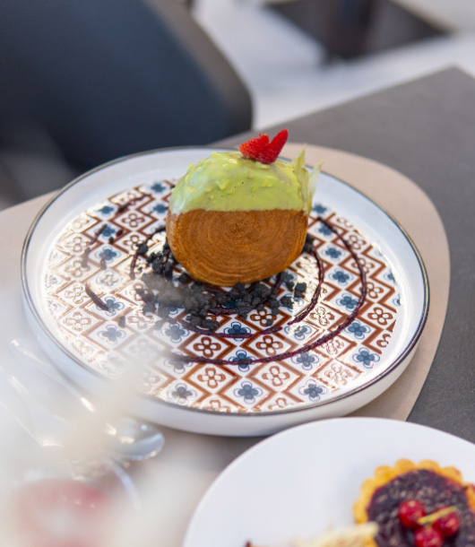 Dessert elegante su piatto decorato, sfera verde con fragola, atmosfera raffinata e invitante.