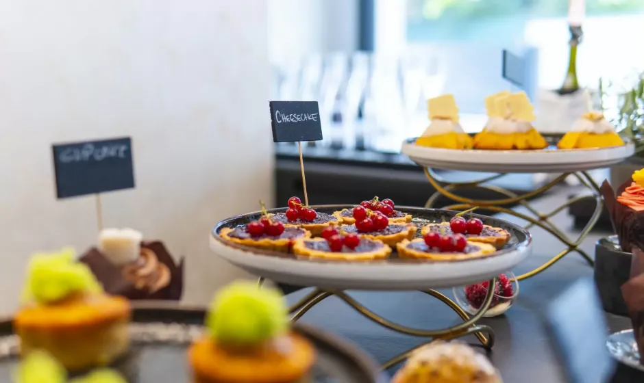 Dolci vari su alzate, tra cui cheesecake con frutti rossi e cupcake.