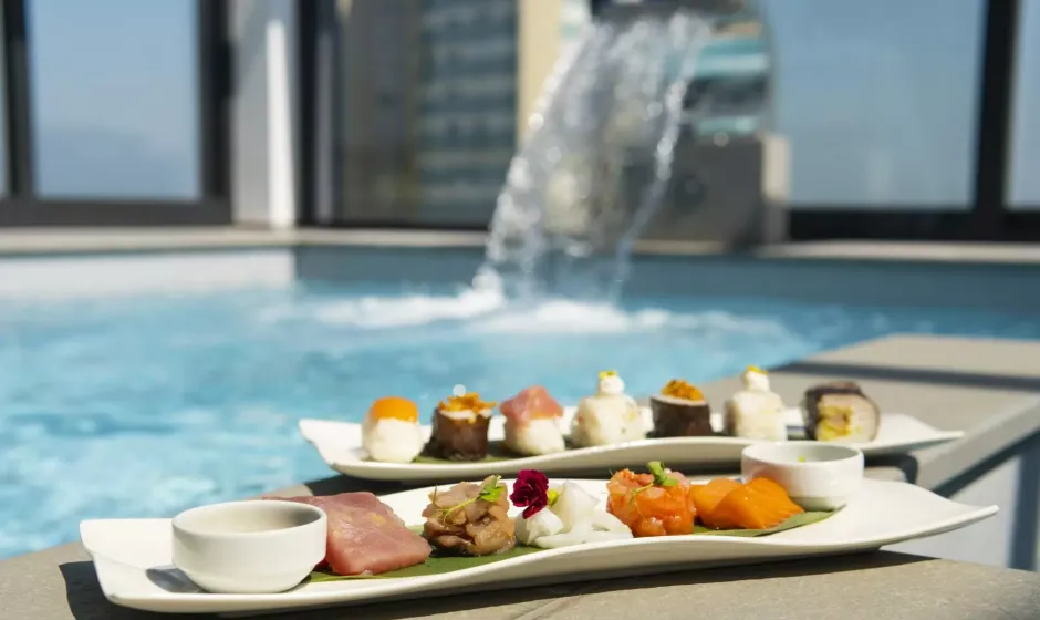 Piatto di sushi vicino a una piscina con cascata sullo sfondo.