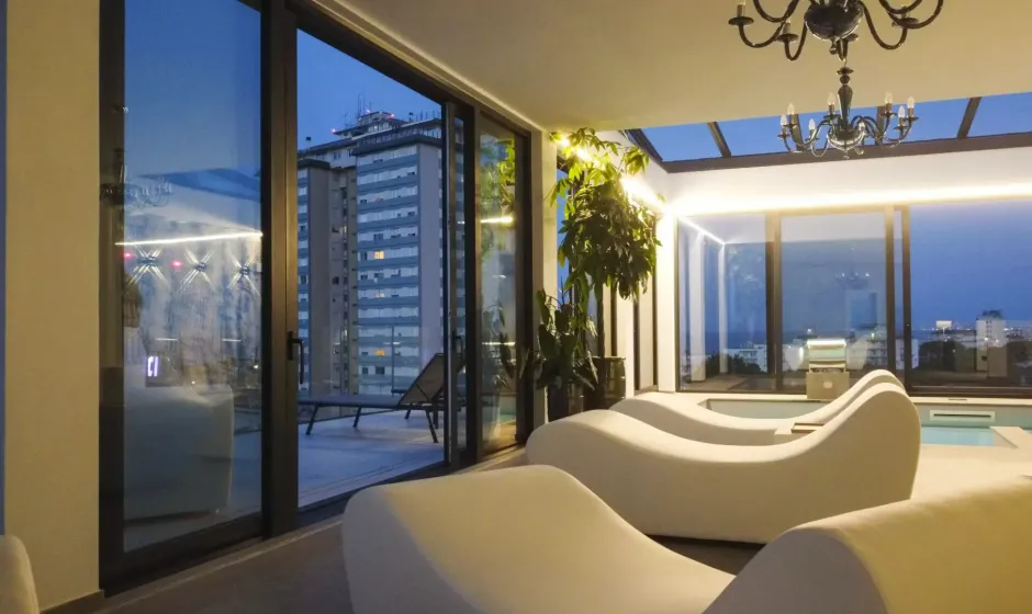 Sala relax moderna con chaise longue e vista su grattacielo.