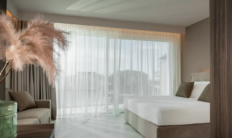 Camera moderna con letto, divano e tende trasparenti.
