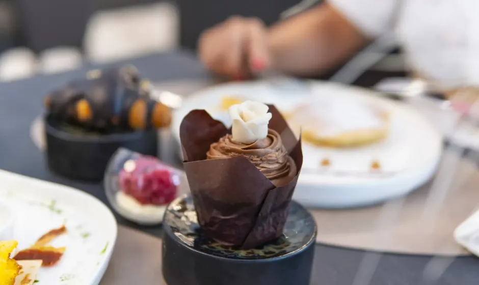 Cupcake al cioccolato con decorazione floreale, su piatto nero elegante.
