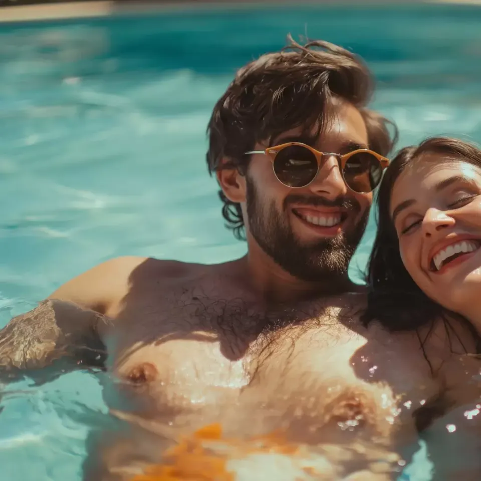 Coppia sorridente si rilassa in piscina, godendosi il sole estivo.