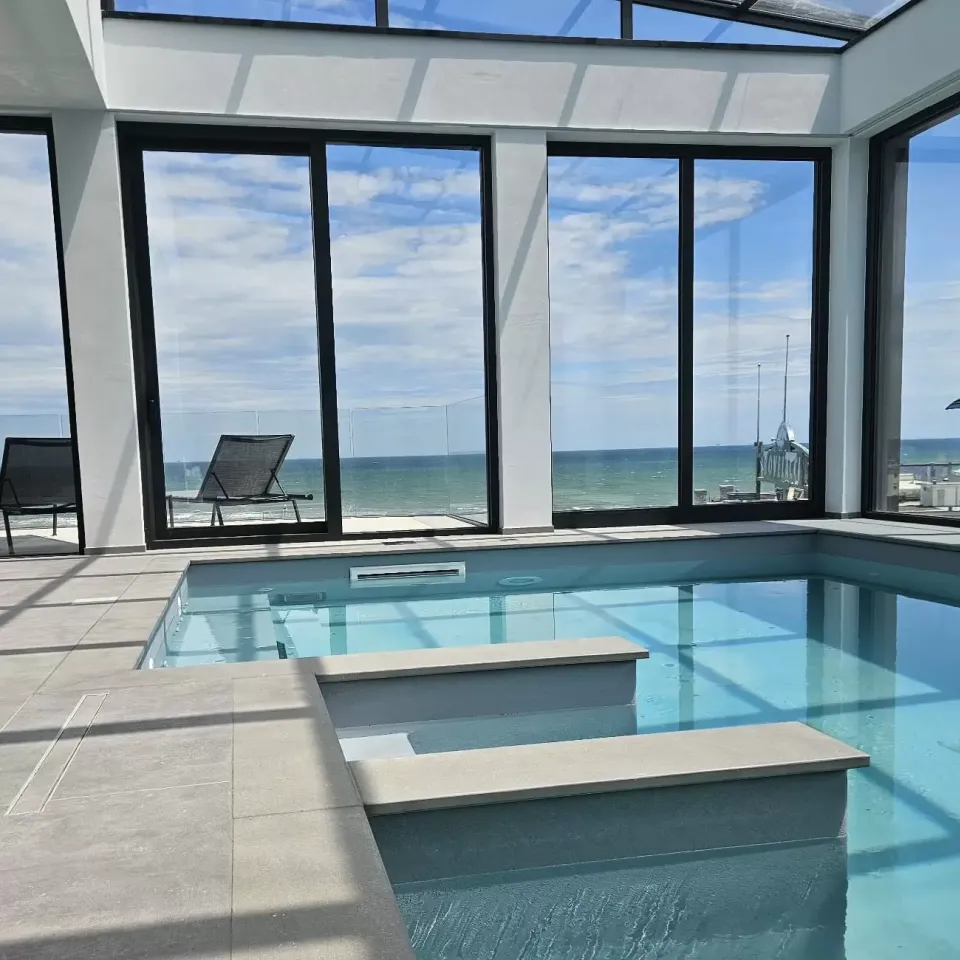 Piscina interna con vista mare, ampie vetrate, design moderno e luminoso.
