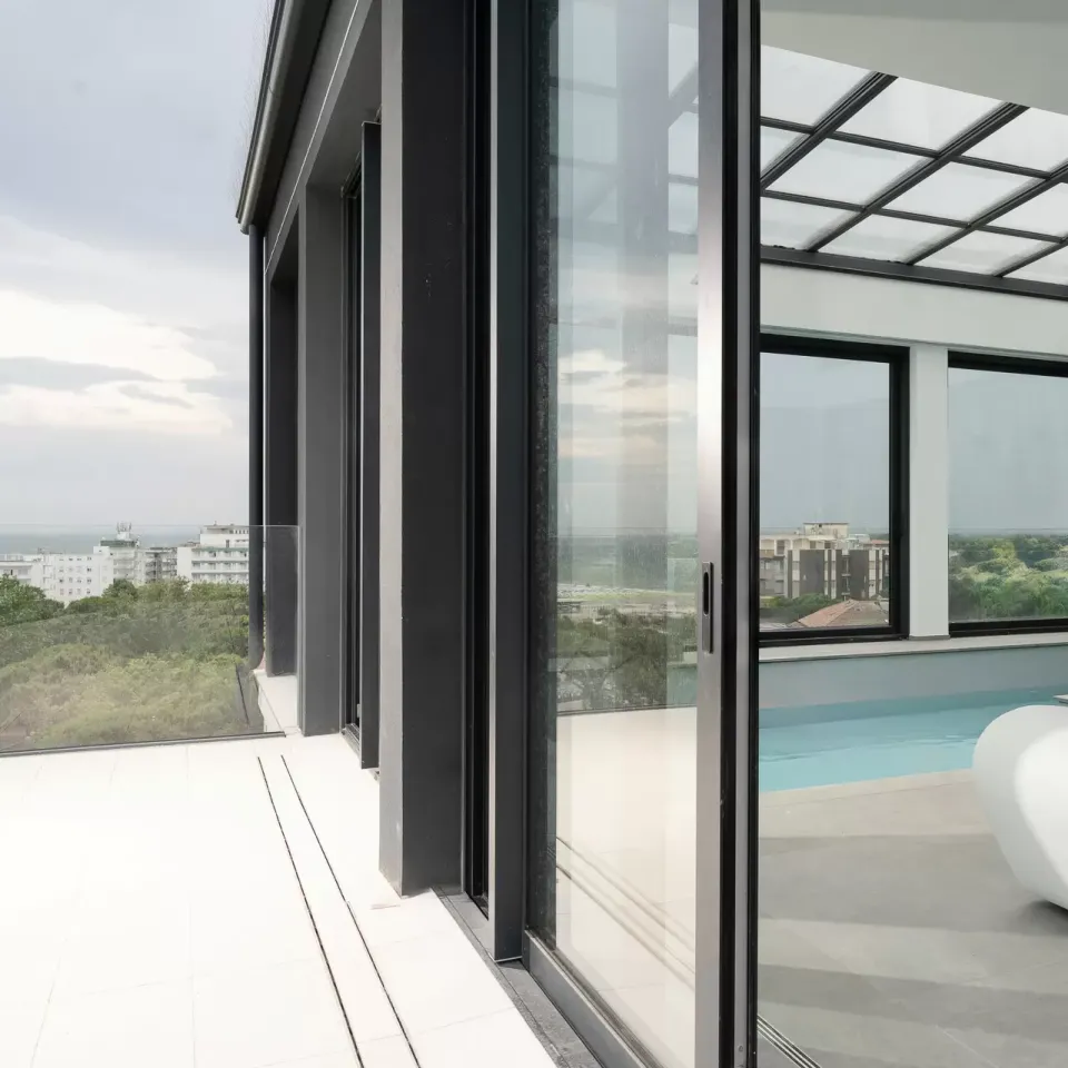 Moderno attico con piscina interna, ampie vetrate e vista panoramica.