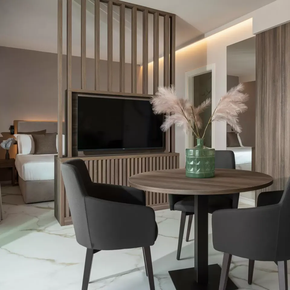 Elegante soggiorno moderno con tavolo rotondo, sedie nere e divisorio in legno.