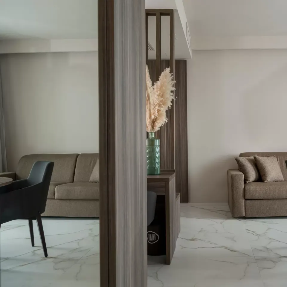 Soggiorno moderno con divani marroni, tavolo rotondo e decorazioni di pampas in vaso verde.
