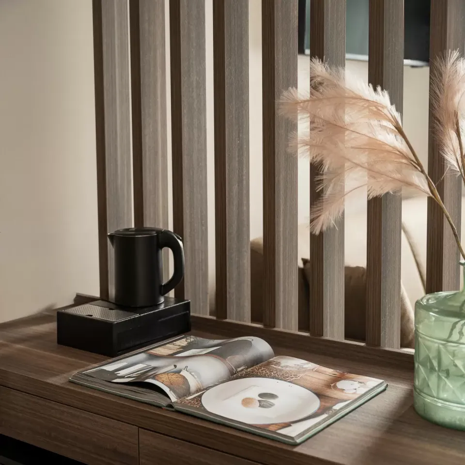 Scrivania elegante con libro aperto, vaso decorativo e bollitore nero su sfondo moderno.